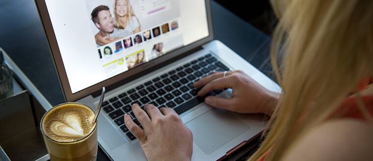 En kvinna sitter vid en dator och surfar på en sajt för nätdejting.