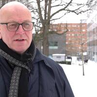 Polischef Erik Nord. En man i rock, halsduk och glasögon, kalt huvud, stående framför polishuset i Göteborg.