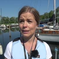 Jenny Blomberg, sjösäkerhetsexpert på Transportstyrelsen, står framför båtar i en hamn. Hon berättar om säkerhet till sjöss.