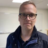 Man med glasögon och blå jacka. Heter Henrik Starkman och är rektor
