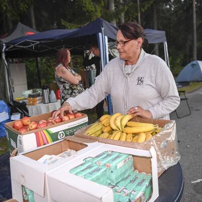 Kvinna står och gör i ordning lådor med frukt.