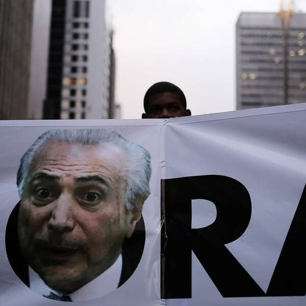 En demonstrant håller upp en baner med president Temers bild på.