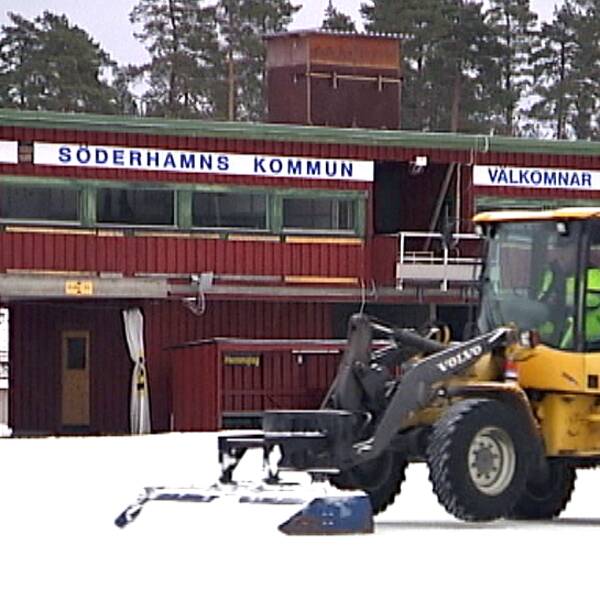 En traktor skottar bort snö från en is.