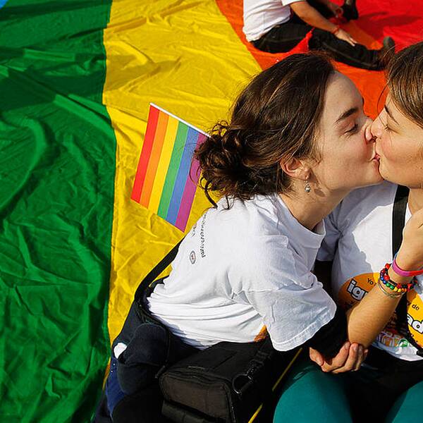 Två unga kvinnor kysser varandra.