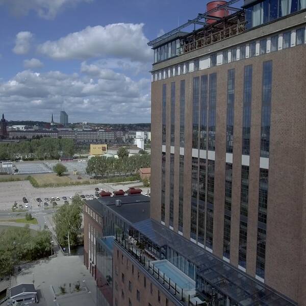 Gammal fabriksbyggnad, ett ångkraftverk i Västerås och Västerås i bakgrunden. 
