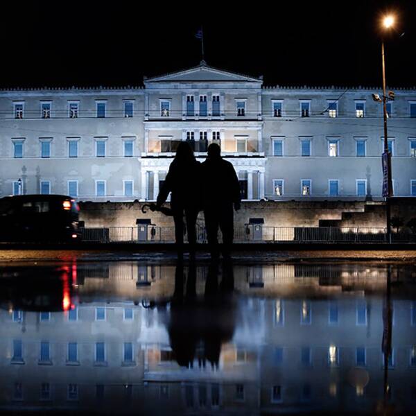 The illuminated Greek Parliament building ahead of the Nov. 14 World Diabetes Day, is reflected on a rain-soaked pavement as a couple wait to cross a street in Athens on Monday, Nov. 11, 2013. (Petros Giannakouris)