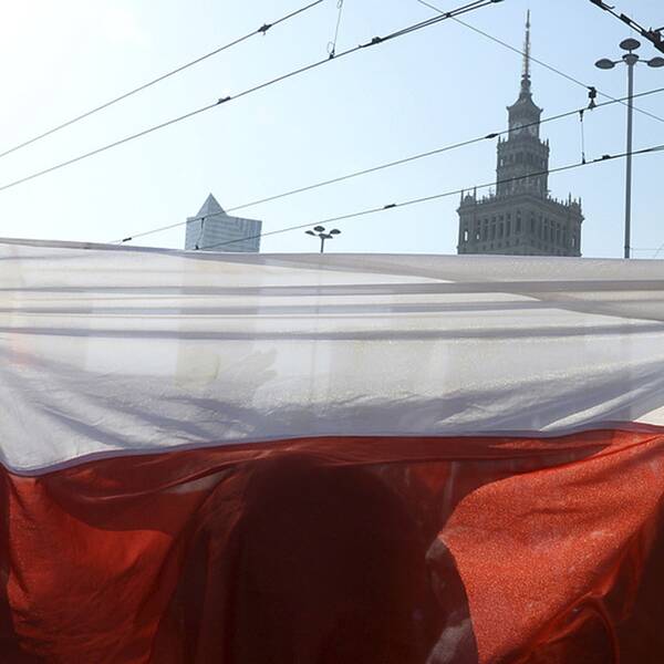En man håller upp en polsk flagga i Warsawa.