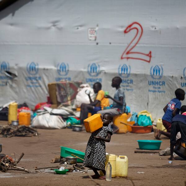 En flicka dricker vatten ur en dunk i ett flyktingläger i norra Uganda.