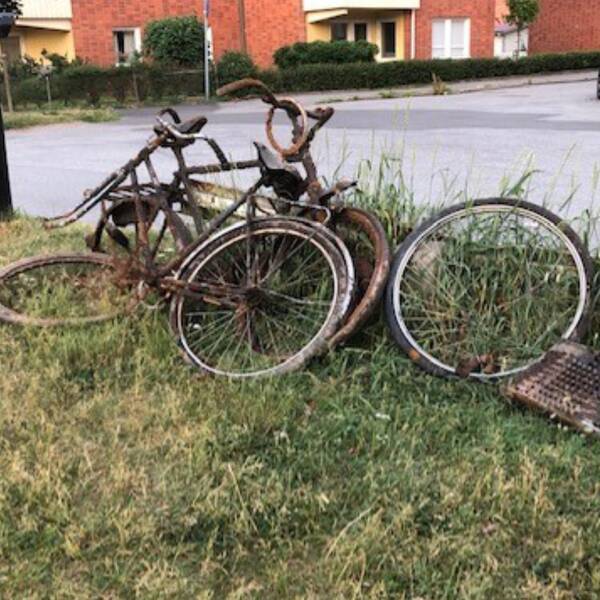 Rostiga cyklar står lutade mot ett räcke.