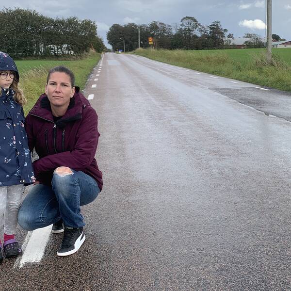 Flicka och mamma står utmed landsväg.