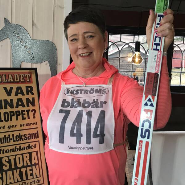 Medelålders kvinna som håller upp löpsida från aftonbladet och ett par skidor