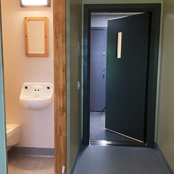Interiör bild av en häktescell i Kriminalvårdens häkte i Växjö, fotograferat mot toaletten och dörren som står på glänt.