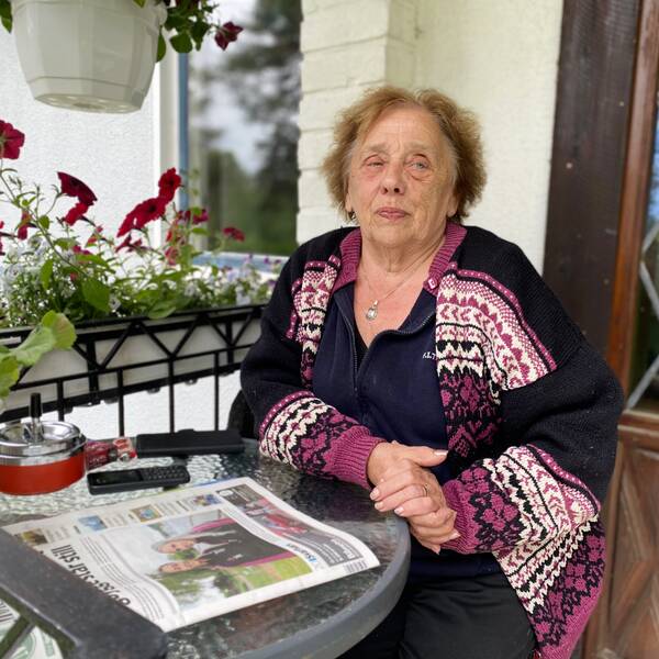 En äldre dam sitter på sin altan med en tidning framför sig efter att hon fått komma tillbaka sitt hem. 