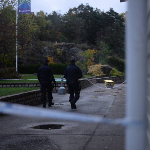 Två polismän utanför en lägenhet.