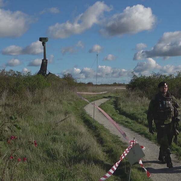 Två militärer som går beväpnade på en stig i Klagshamn natureservat med en radar i bakgrunden som bevakar luftrummet över Malmö.