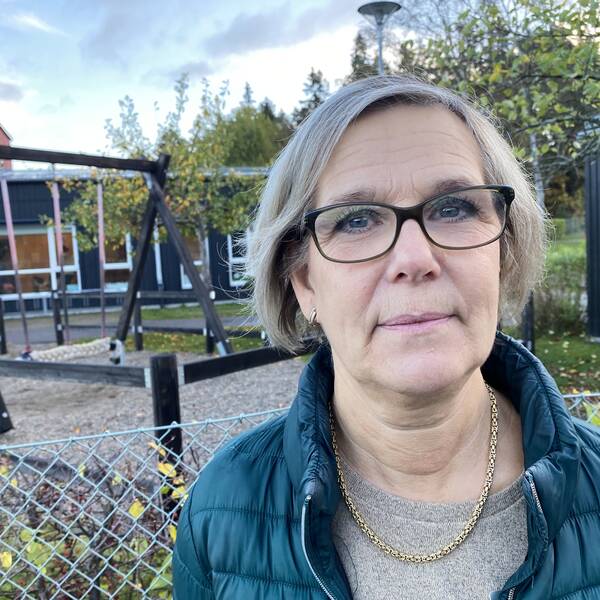 Carin Lindberg i grön täckjacka står utanför förskolans lekpark.