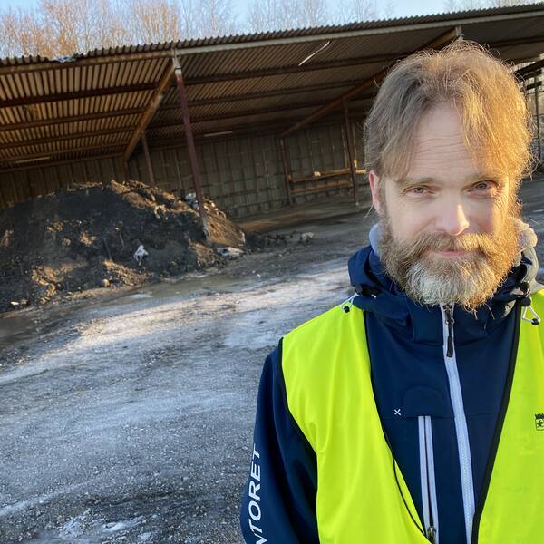 David Aronsson i varselväst står framför en stor gråsvart hög med nedmalda batterier.