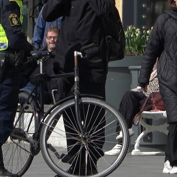 Polis som pratar med en person som håller i sin cykel.