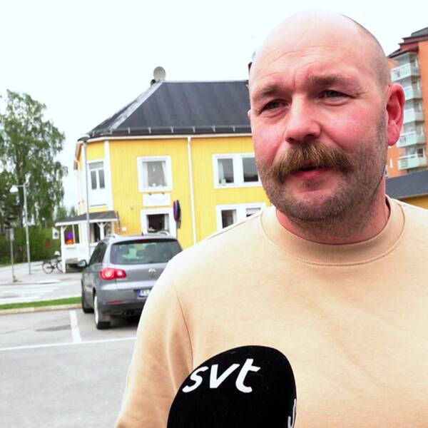 en medelålders man med mustasch intervjuas på en parkering
