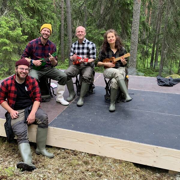 Fyra personer på en liten scen i skogen