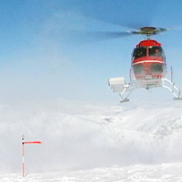 En helikopter flyger i fjällvärlden.