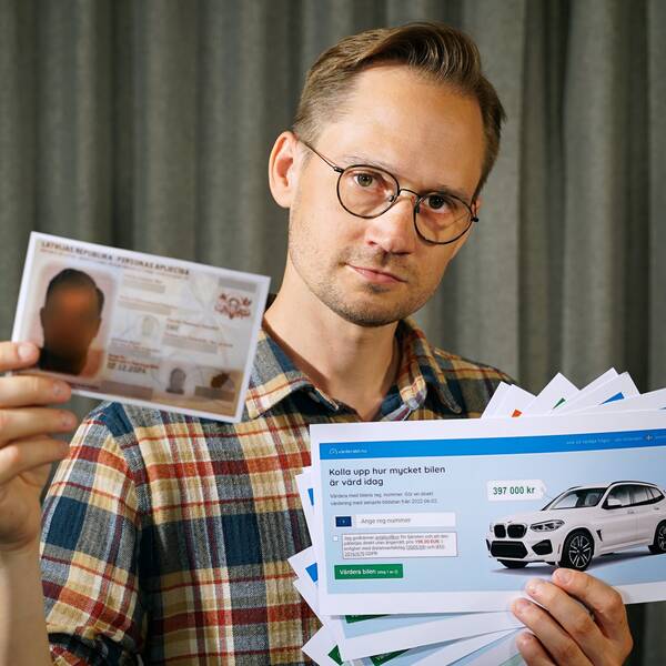 En person håller upp lappar med reklam för bilvärderingsfirmor. 