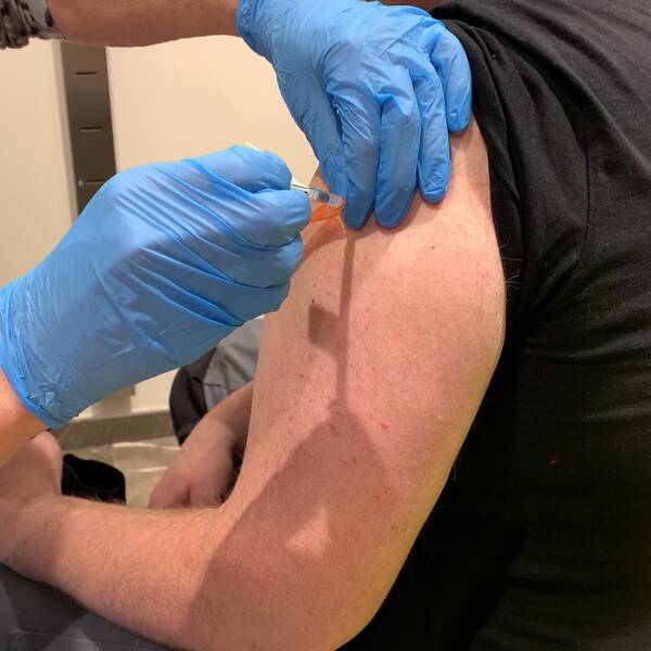 En man som får en vaccinspruta i armen.