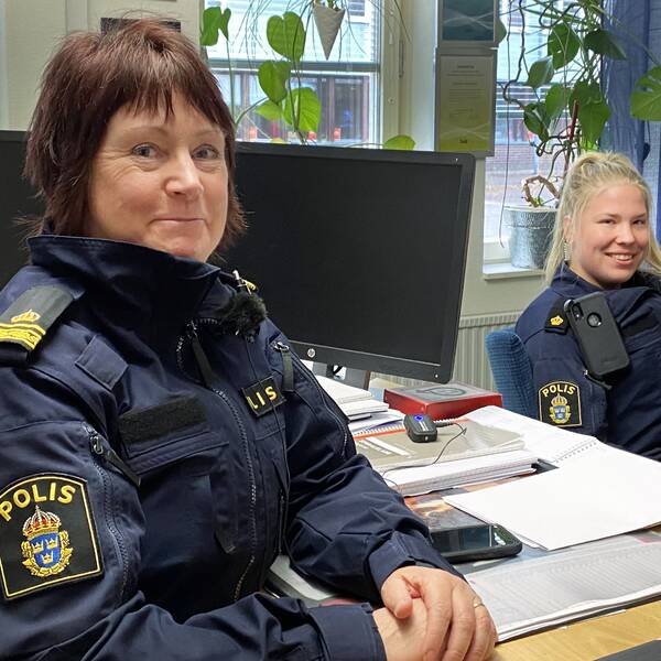 Susanne Lindström, områdespolis i Krylbo, sitter till vänster vid ett skrivbord iklädd polisuniform. Till höger sitter Elsa Edvardsson, som snart jobbat som polis i Avesta i ett år. De berättar vad polisen gör för att locka personer i Avesta till polisyrket.