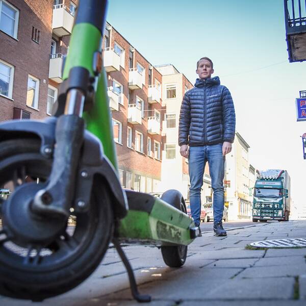 Johan Larsson, enhetschef på Gävle kommun, framför en elsparkcykel parkerad mitt på en trottoar.