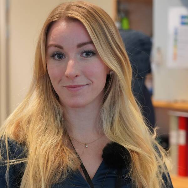 En blond tjej står inne på ett kontor.