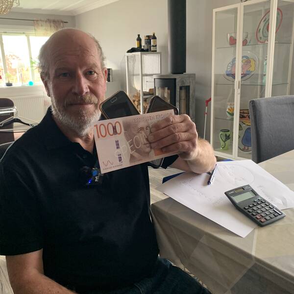 Man som håller i tusenlapp och två mobiltelefoner