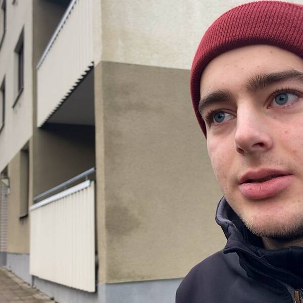 Bild på Johannes Andersen, student som bor vid platsen där dödsskjutningen inträffade på campus i Sätra på lördagskvällen. Han har på sig en röd mössa och står framför ett bostadshus.