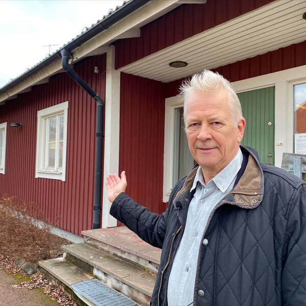 en vithårig man som är kommundirektör i Mora kommun, pekar mot ett hus som kommunen ska dra ner värmen i – så att de spar pengar.