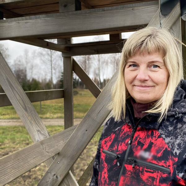 en medelålders kvinna vid ett jakttorn på åkermark