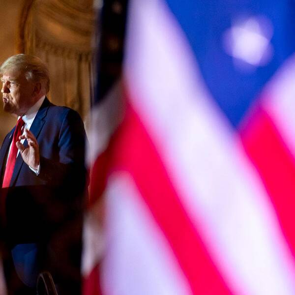 Donald Trump talar vid amerikanska flaggor.