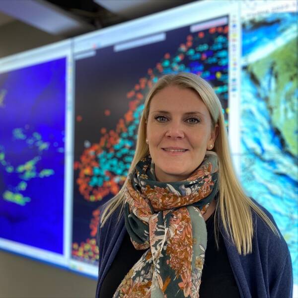 Meteorologen Linnea Rehn Wittskog står framför en helbildsskärm med väderbilder.