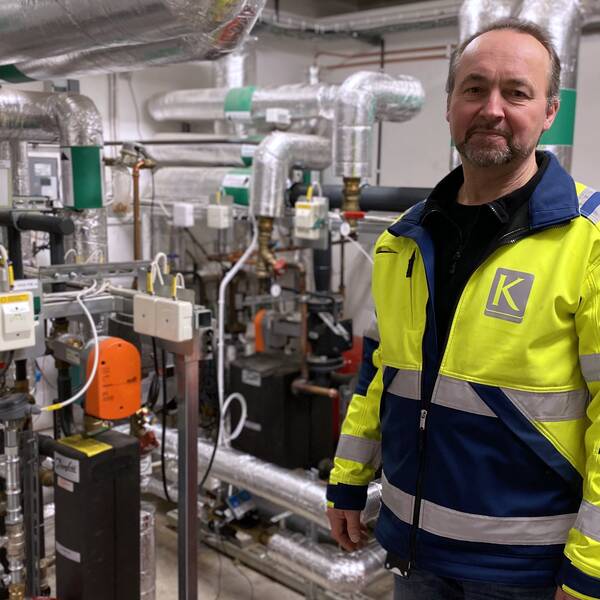 Kenneth Ahlström från Kopparstaden står i ett rum med fjärrvärmeledningar