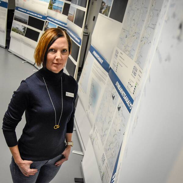 Emelie Johansson, projektledare Svea vind offshore, står omgiven av bilder och information i deras showroom.
