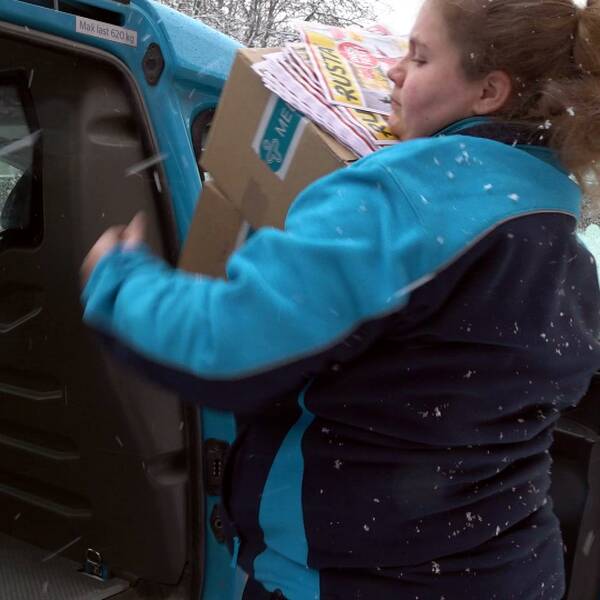 Brevbäraren Jennifer plockar ut paket och post ur sin arbetsbil i snöväder