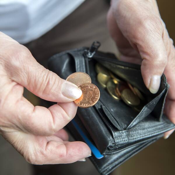 Hand som plockar ut mynt ur plånbok.