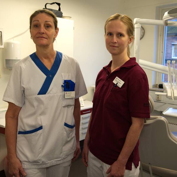 två kvinnor i vårdens arbetskläder står i ett besöksrum hostandvården