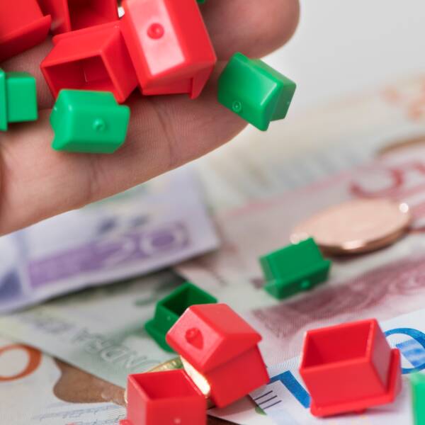 Röda och gröna små miniatyrhus ligger på pengarsedlar
