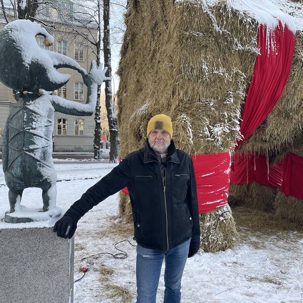 Håkan Haglöf står lutad mot en staty som ger lillbocken långnäsan. 