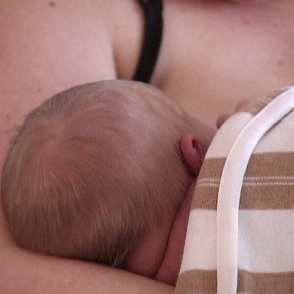 Bebis ligger i sin mammas famn.