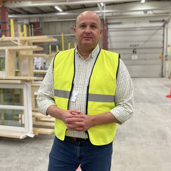 Peter Rhensbo, vd på Norrlands trähus, står i en lagerlokal med brädor i bakgrunden och berättar om den ekonomiskt svåra situationen för hans företag.