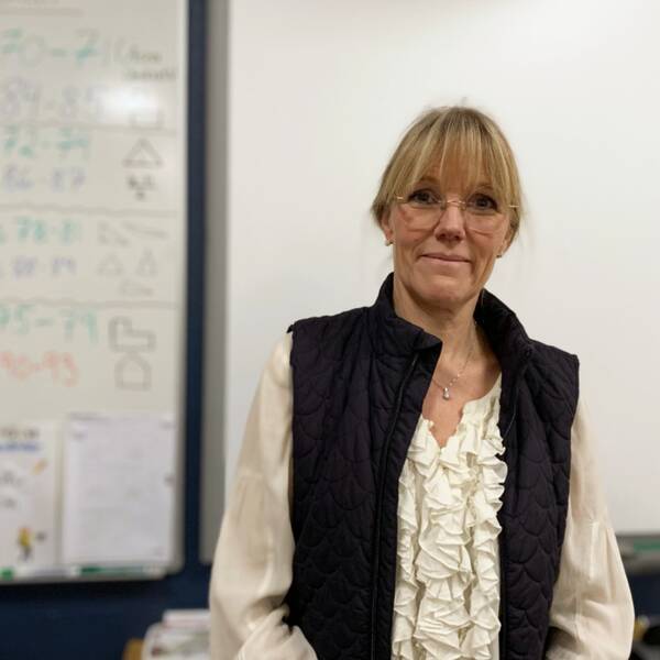 Lotta S Karlsson står framför en whiteboardtavla i ett klassrum.