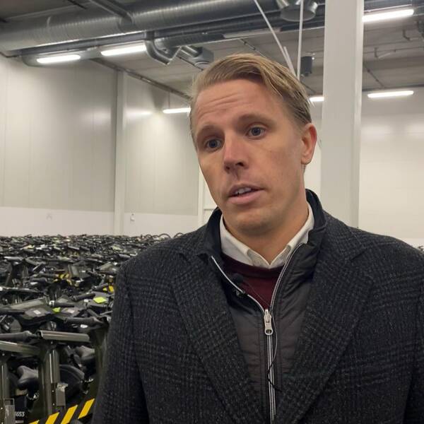 Daniel Mohlin, manager på företaget Inurba Mobility, står i en lagerlokal framför hundratals parkerade elcyklar.