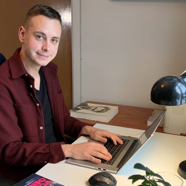 Författaren Backolars Johan Hermansson sitter vid sitt skrivbord framför sin laptop