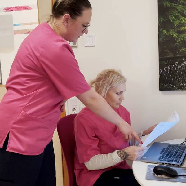 Undersköterskorna Rebecca Ingvarsson och Eva Lindmark berättar om vad de tror gör att hemtjänsten i Strömsund får så högt betyg av de äldre. På bilden ser man Rebecca Ingvarsson stå bredvid Eva Lindmark och peka på ett papper. Rebecca har mörkt hår och glasögon och Eva har ljust hår. Båda har rosa tröja på sig.