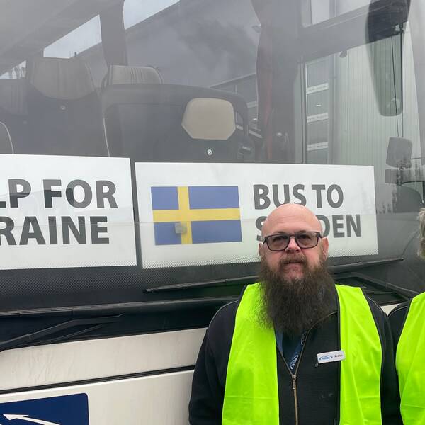 Bild på en man och en kvinna i var sin varselväst framför en buss med skyltar där det står Help for Ukraine och Bus to Sweden. Personerna heter Bobbo Nilsson och Rose-Marie Östergren och körde andra bussen med ukrainska flyktingar från Polen till Sverige